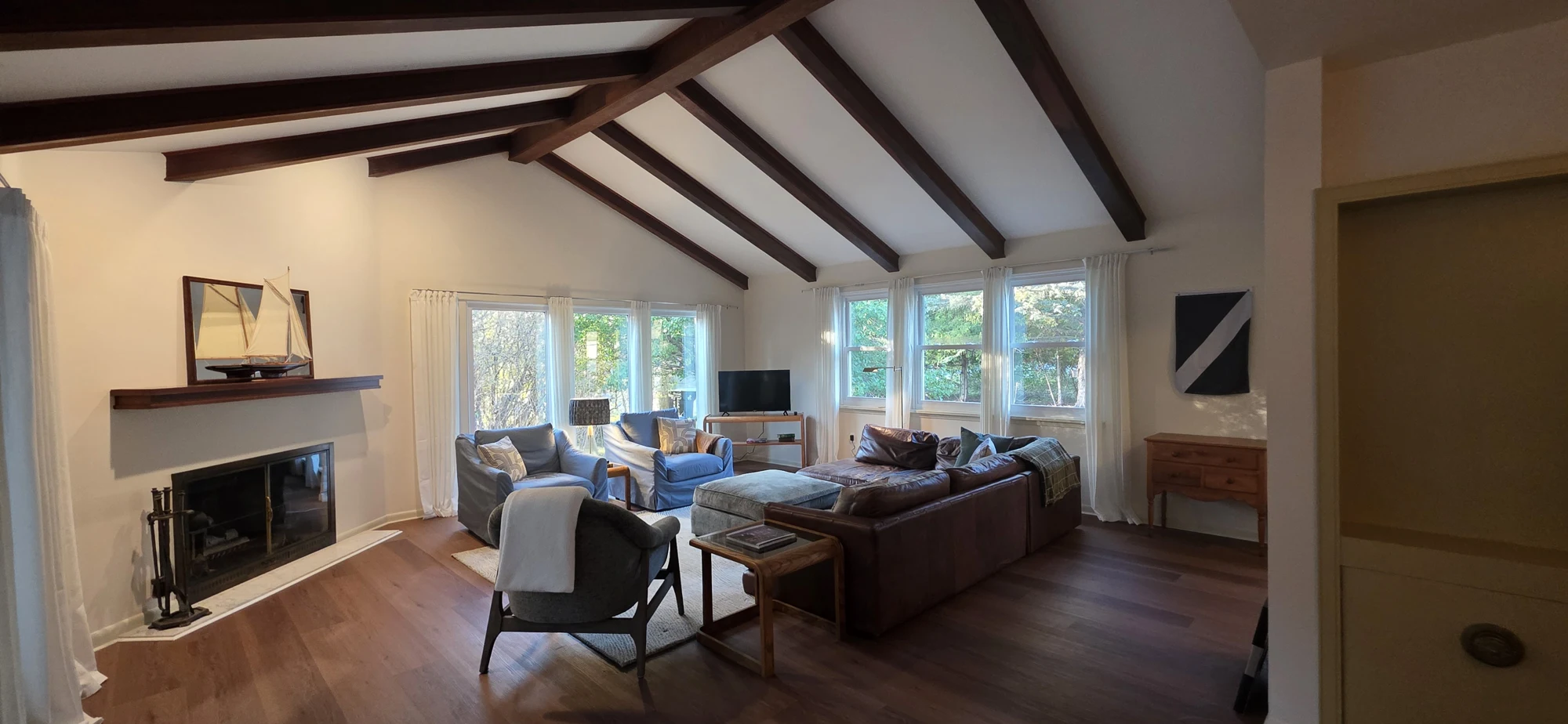 Beamed living room with sofas, a fireplace and doors to the sunroom